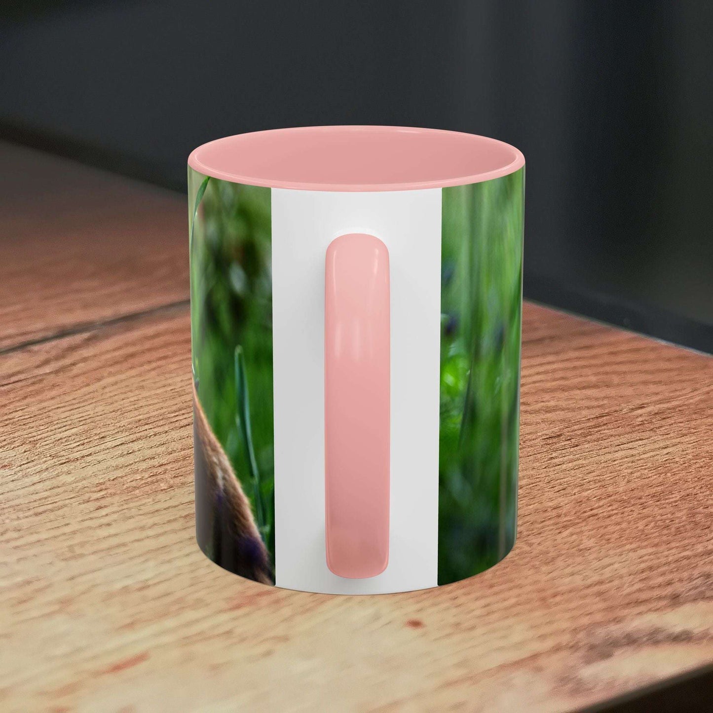 Fox-inspired accent coffee mug on wooden surface with pink handle and nature-themed design.