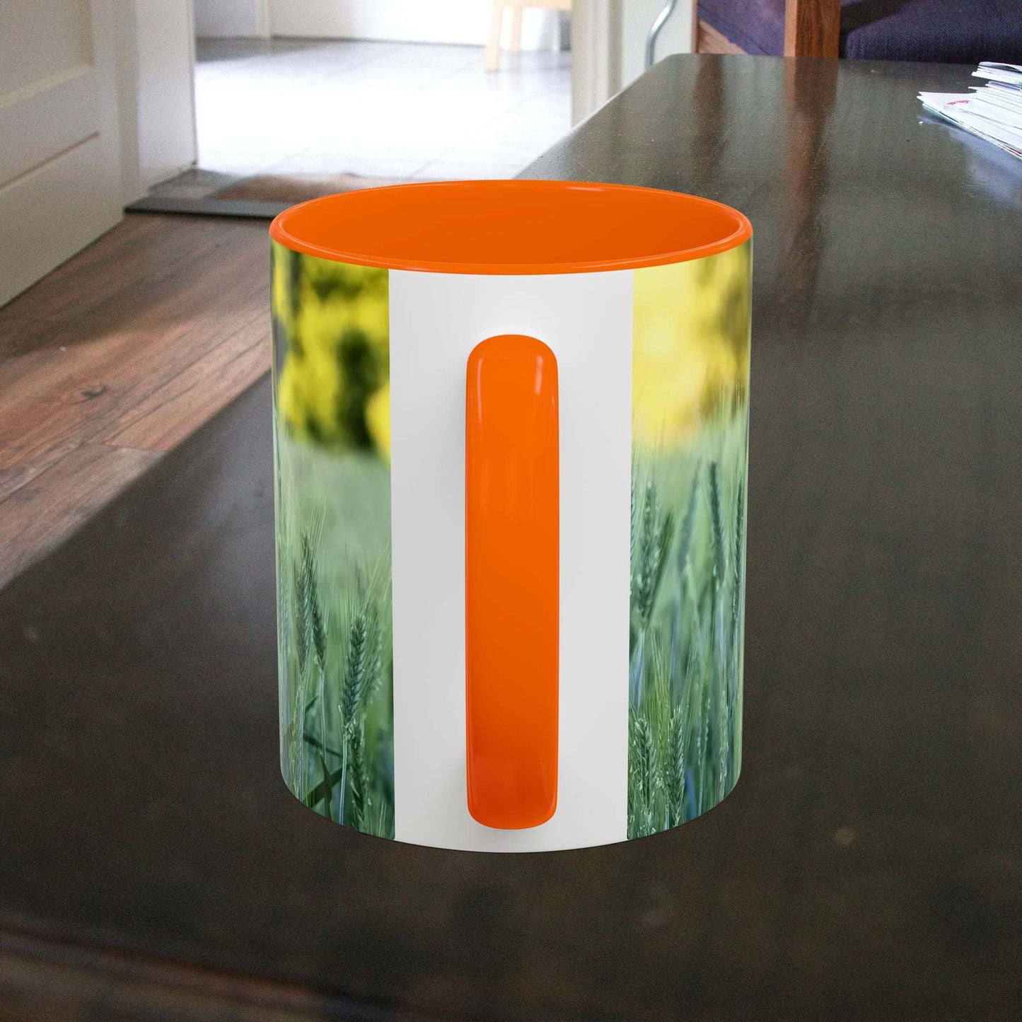 Wheat field design coffee mug on wooden table with orange interior.