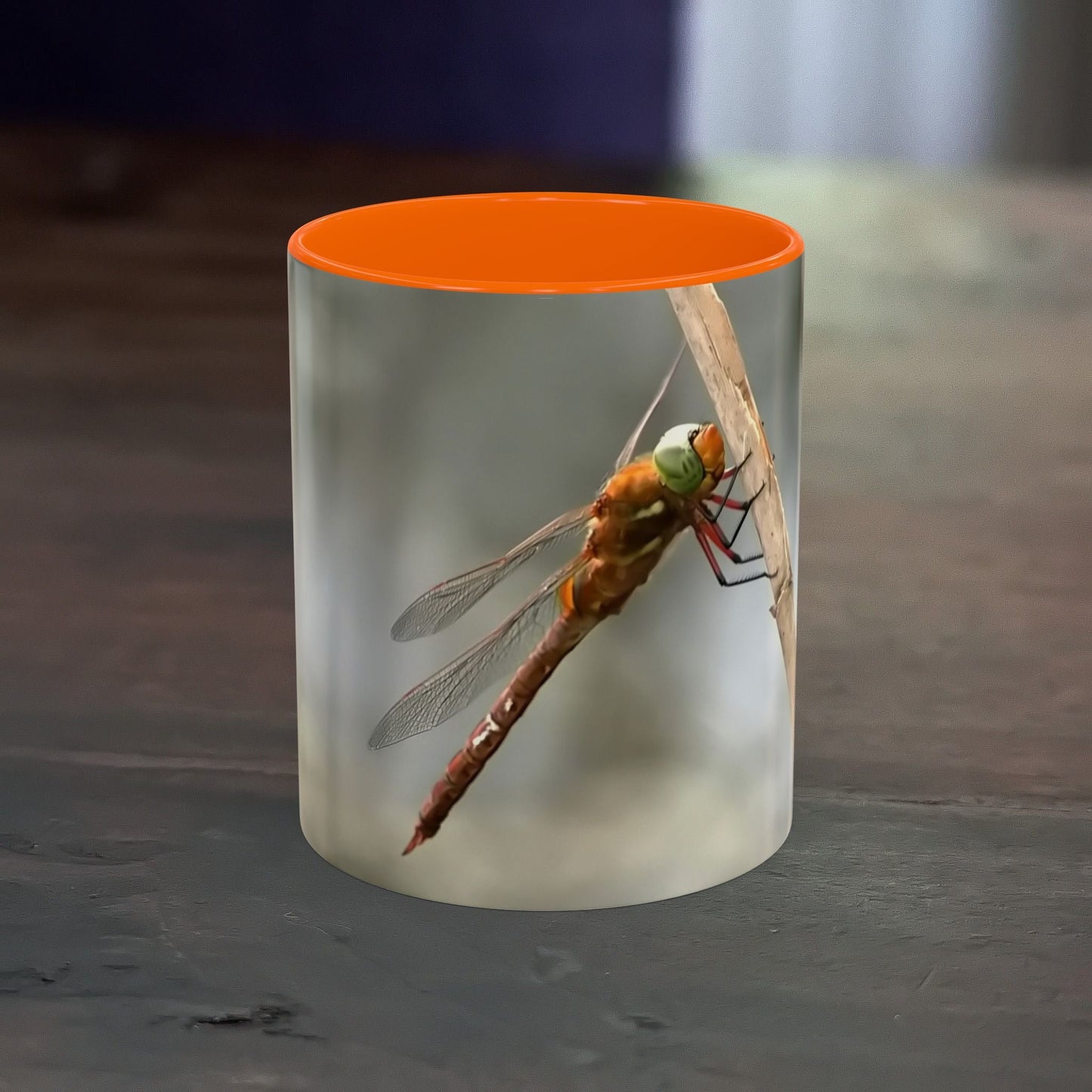 Pretty dragonfly accent coffee mug with vibrant orange interior and contrast handle.