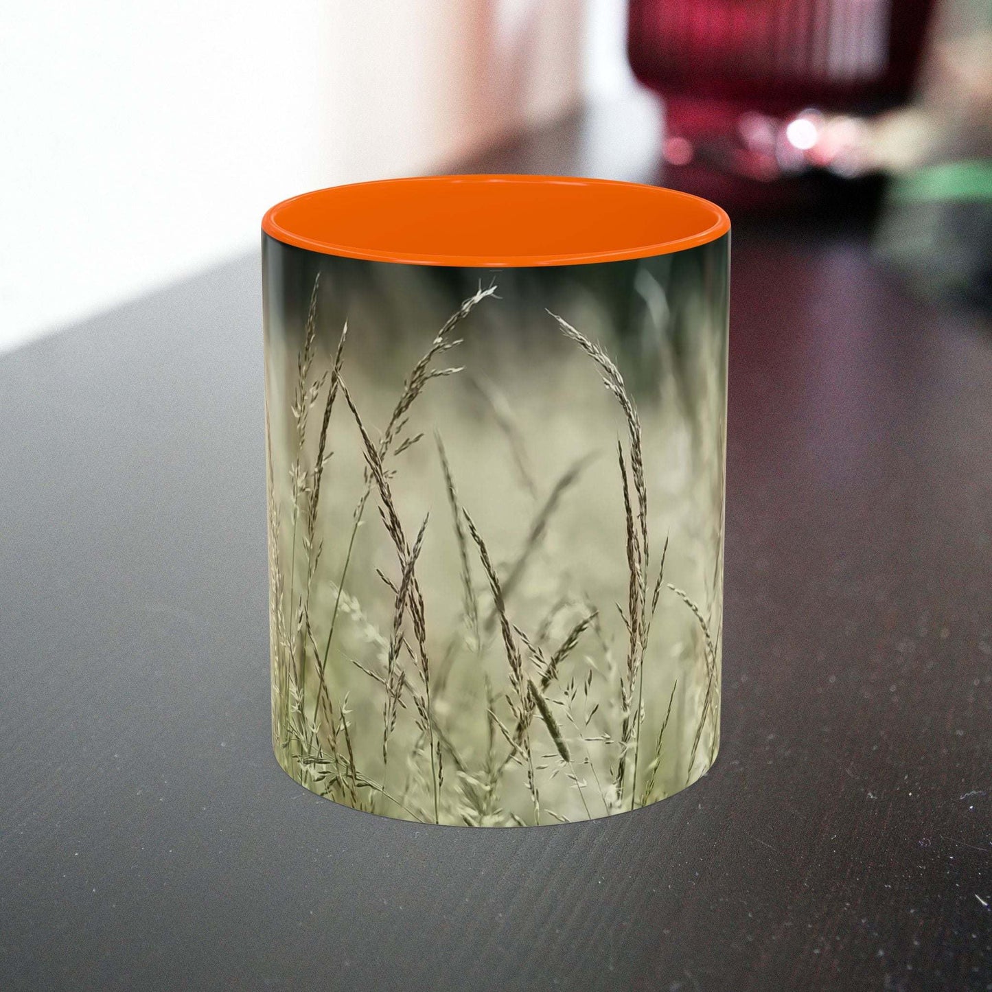 Ceramic mug with flowering grass design on a table.