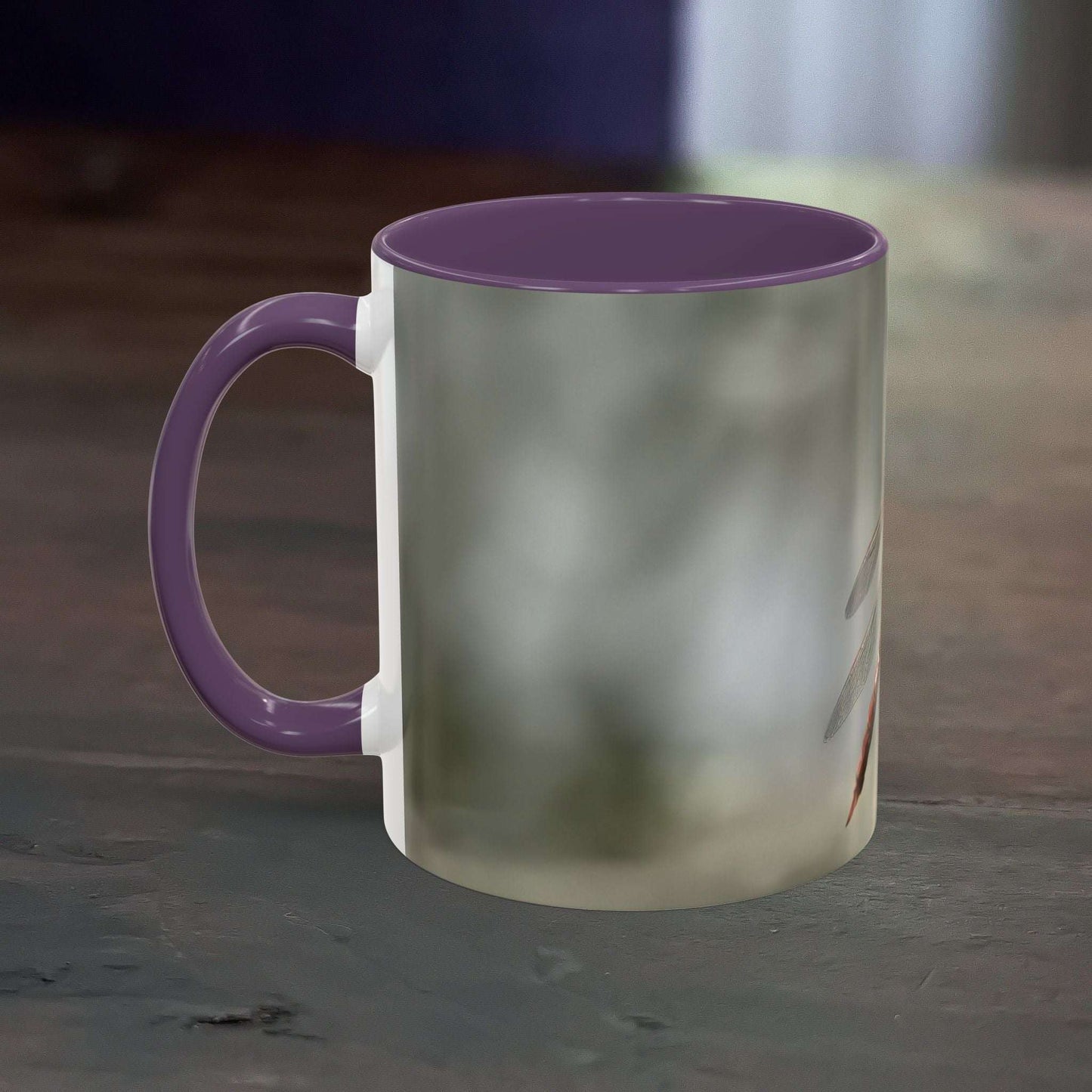 Pretty dragonfly accent coffee mug with purple interior and handle on wooden table.