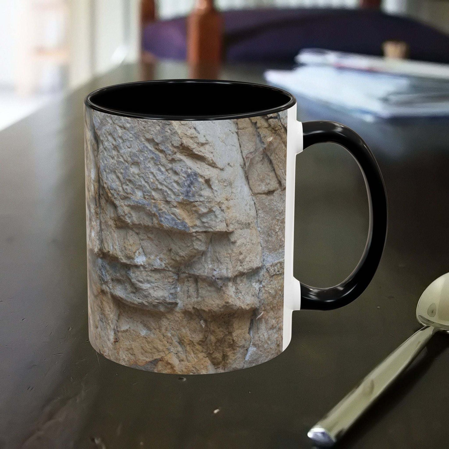 Rocky Mug with falling rocks design on a table, perfect for mountain lovers and outdoor enthusiasts.