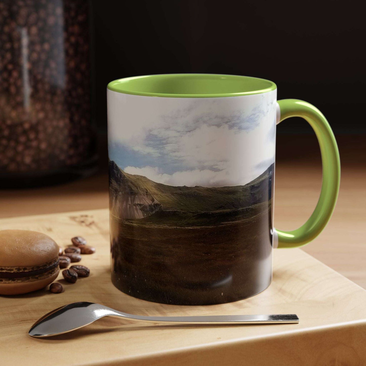 Iceland scenery coffee mug with vibrant colors on wooden table with macaron and spoon.