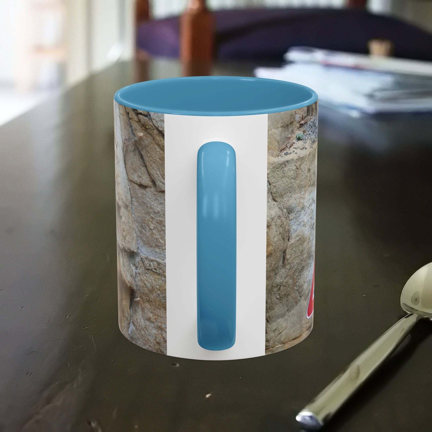 Rocky Mug with mountain design and blue handle on table.