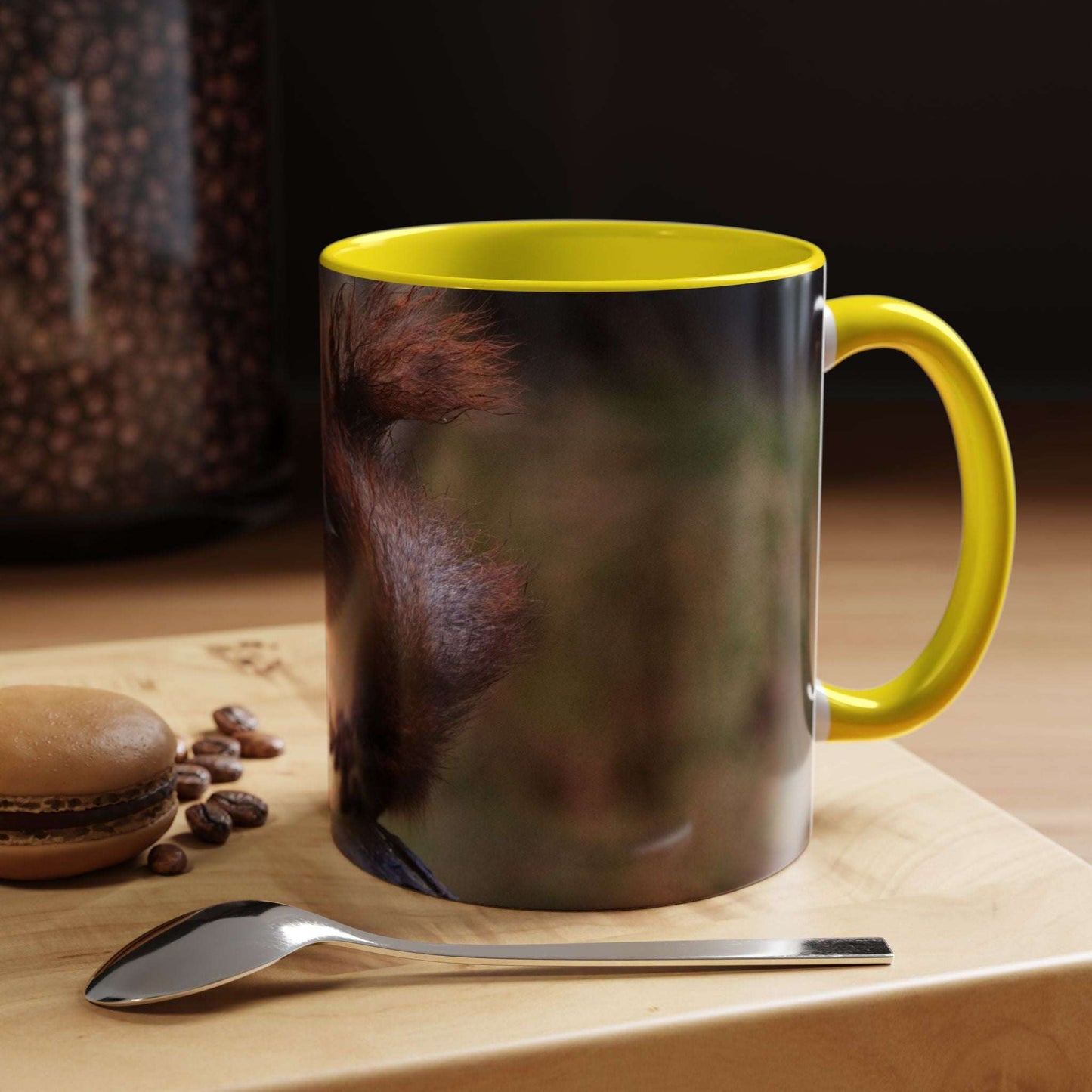 Squirrel Coffee Mug with cute animal design, yellow rim, and handle on a wooden table with coffee beans and a macaron.