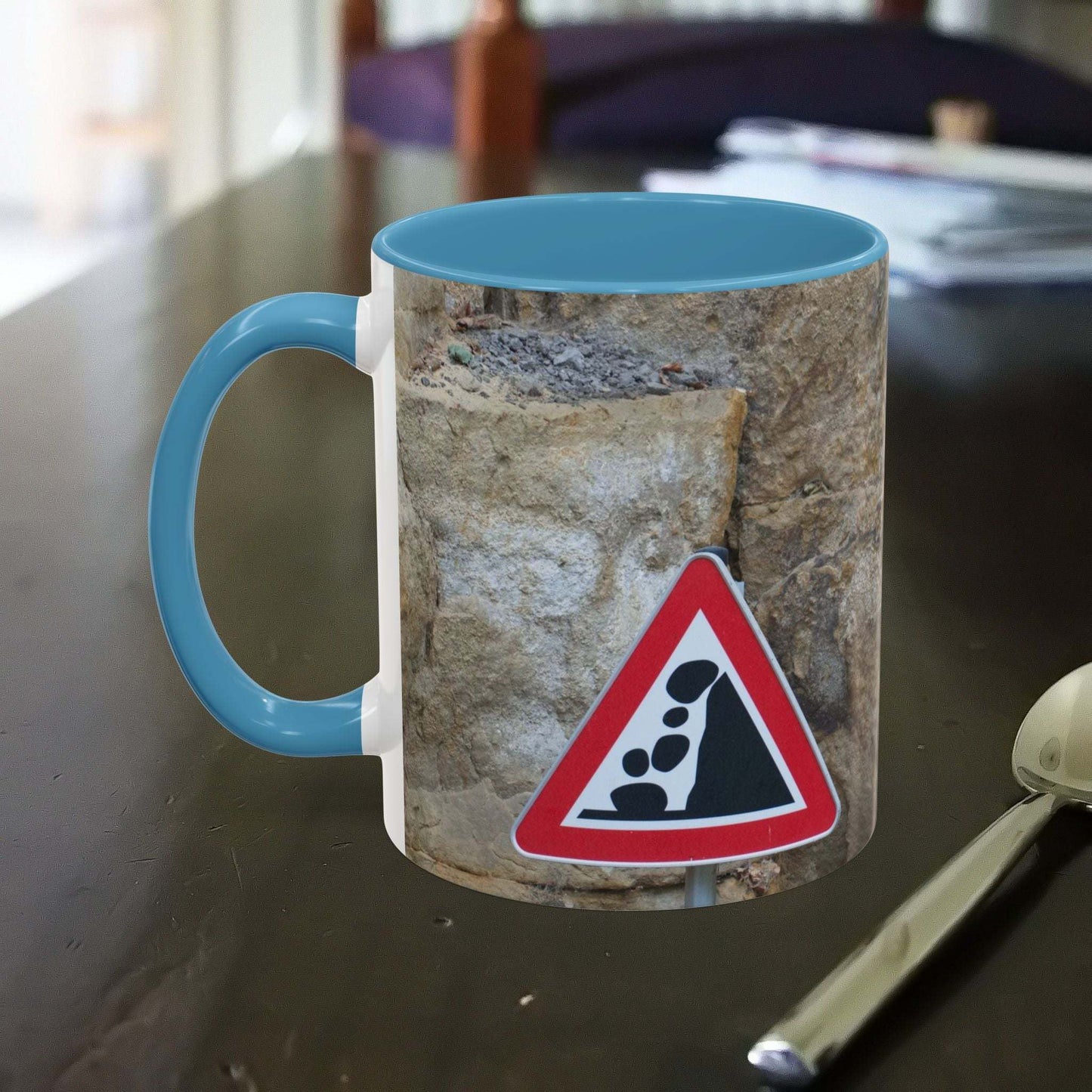 Rocky Mug with mountain design and falling rocks warning sign on a table.