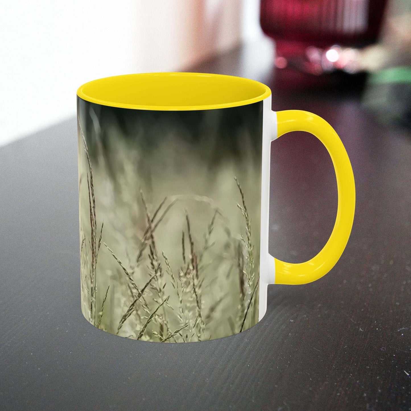 Ceramic mug with flowering grass design and yellow handle.