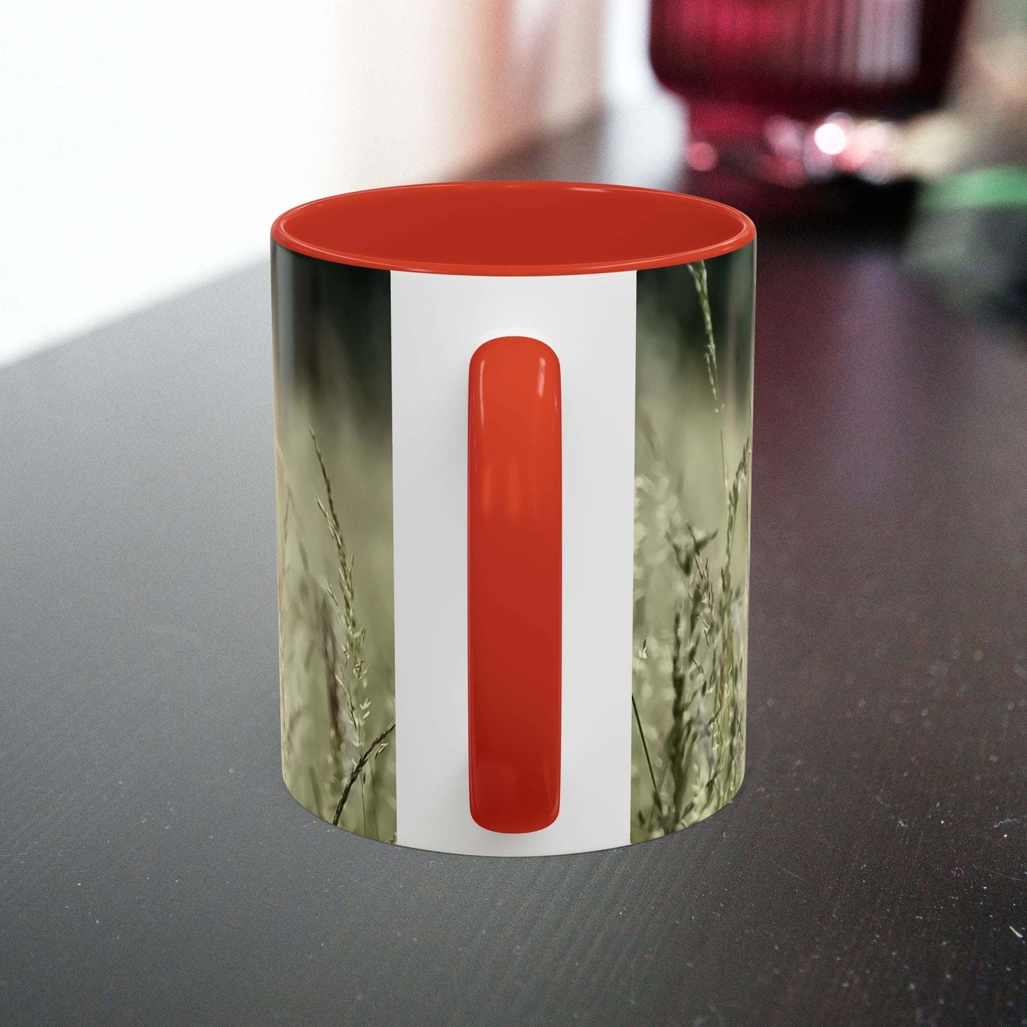 Ceramic mug with flowering grass design and orange handle.