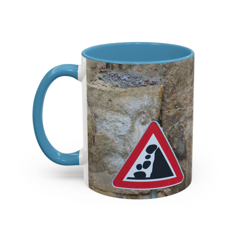 Adventurous 11oz Rocky Mug, Mountain Lovers, Danger of Falling Rocks with a light blue handle and light blue inside on wood.