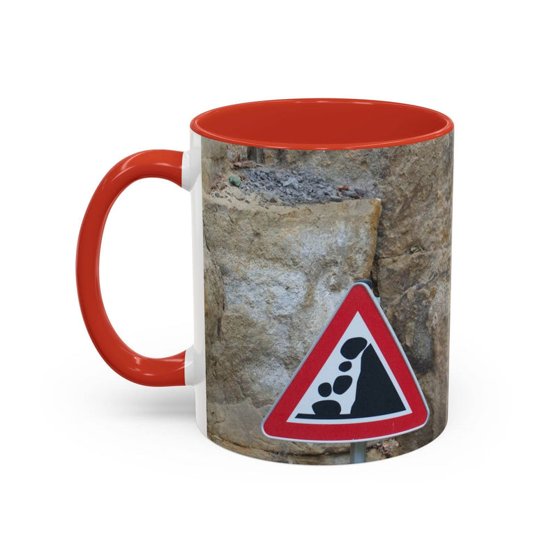 Adventurous 11oz Rocky Mug, Mountain Lovers, Danger of Falling Rocks with a red handle and red inside on a table.