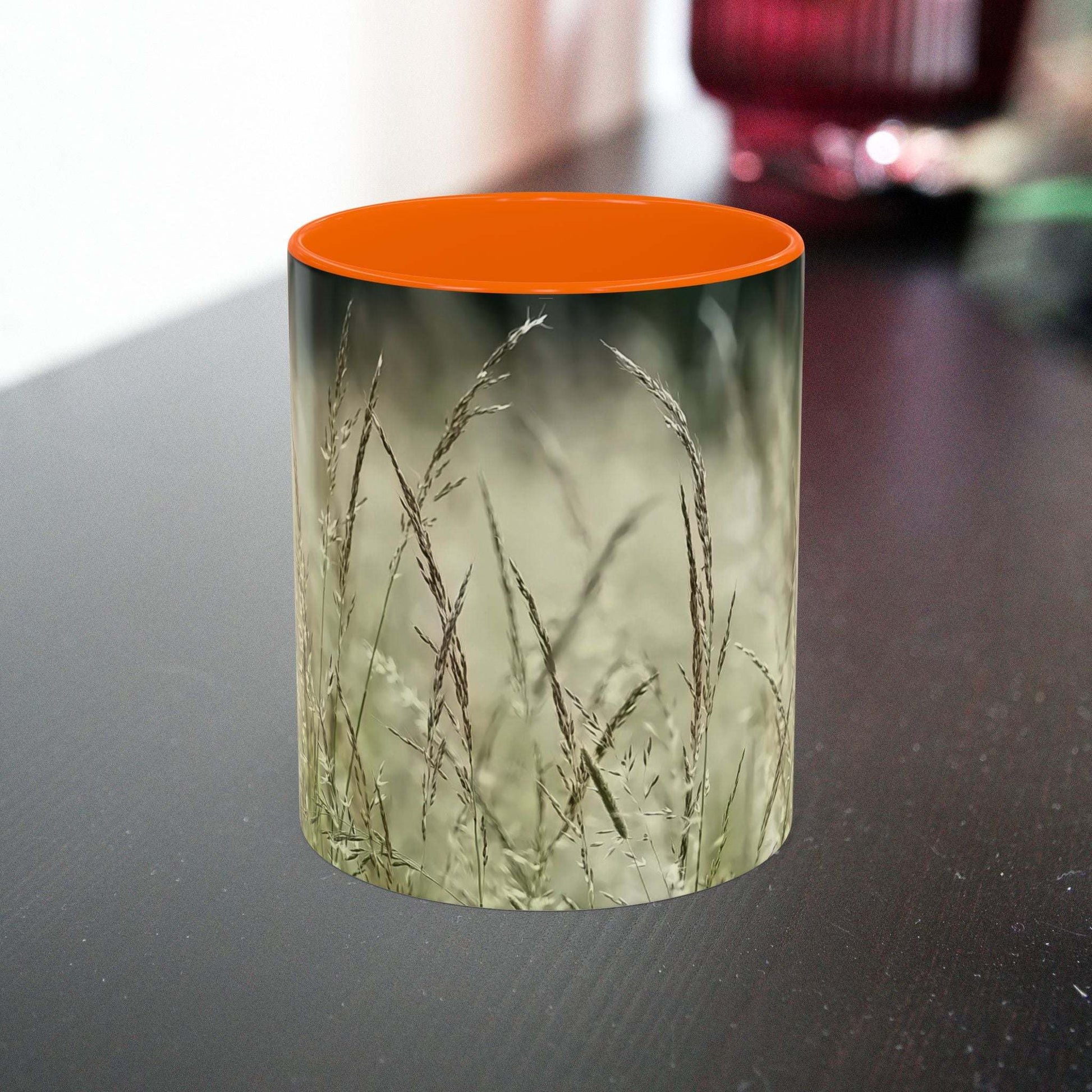 Ceramic mug with flowering grass design on a table.