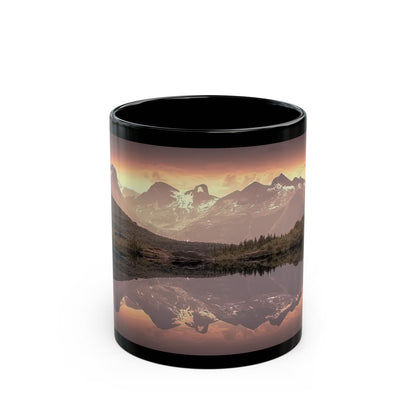 Glossy black 11oz Mountain Reflection Black Mug — Scenic Sunset Lake Coffee Mug next to green botanical plants.