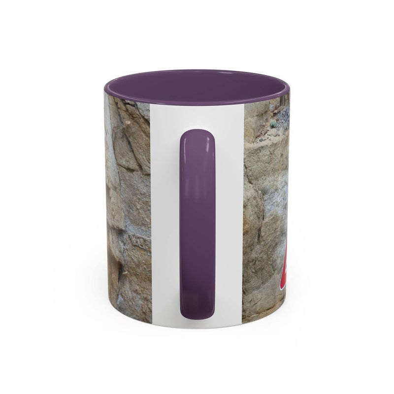 Outdoorsy 11oz Rocky Mug, Mountain Lovers, Danger of Falling Rocks on a placemat, showcasing its purple handle and inside.