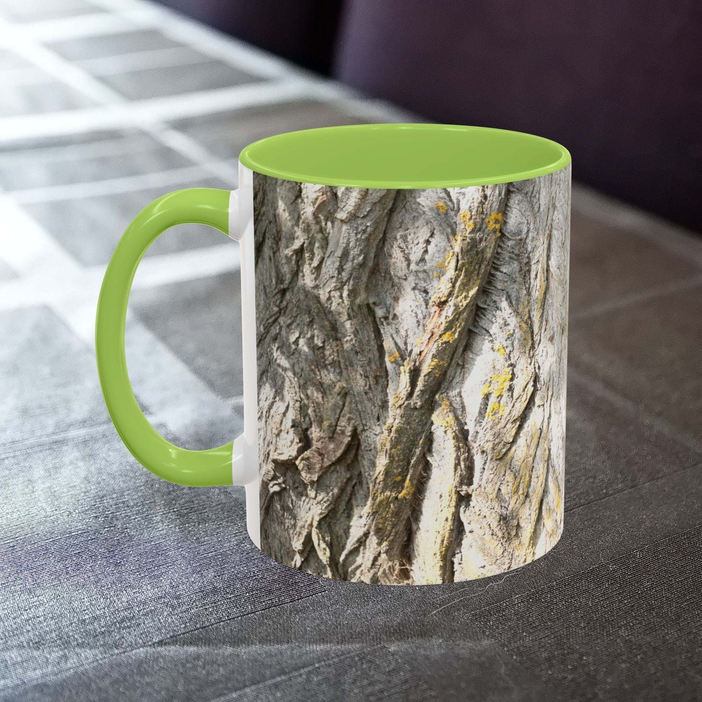 Coffee mug with tree trunk design and green interior on a table.