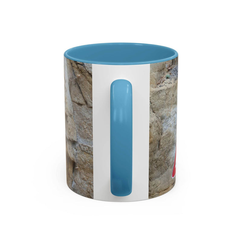 Outdoorsy 11oz Rocky Mug, Mountain Lovers, Danger of Falling Rocks on a stool, showcasing its light blue handle and inside.