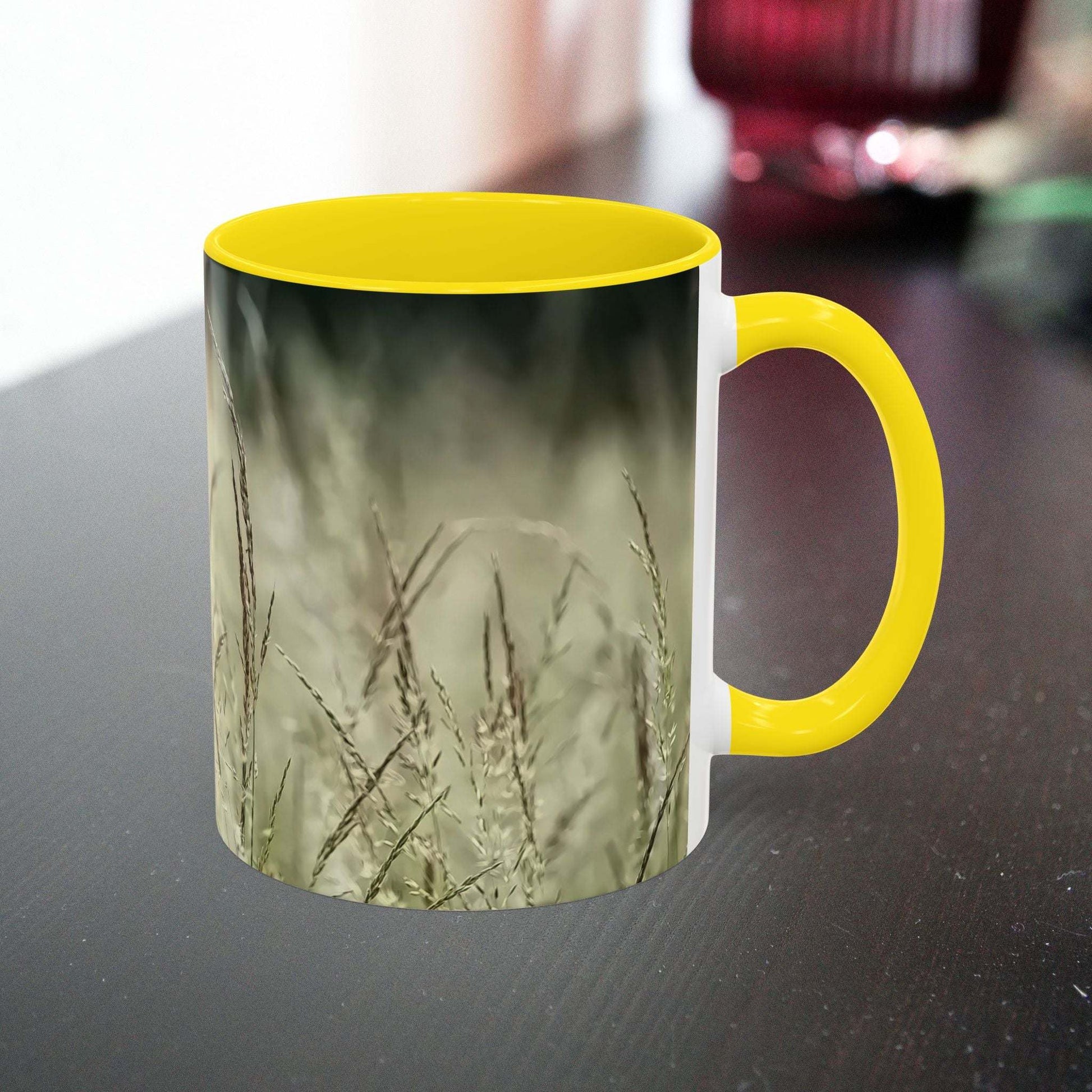 Ceramic mug with flowering grass design and yellow handle.